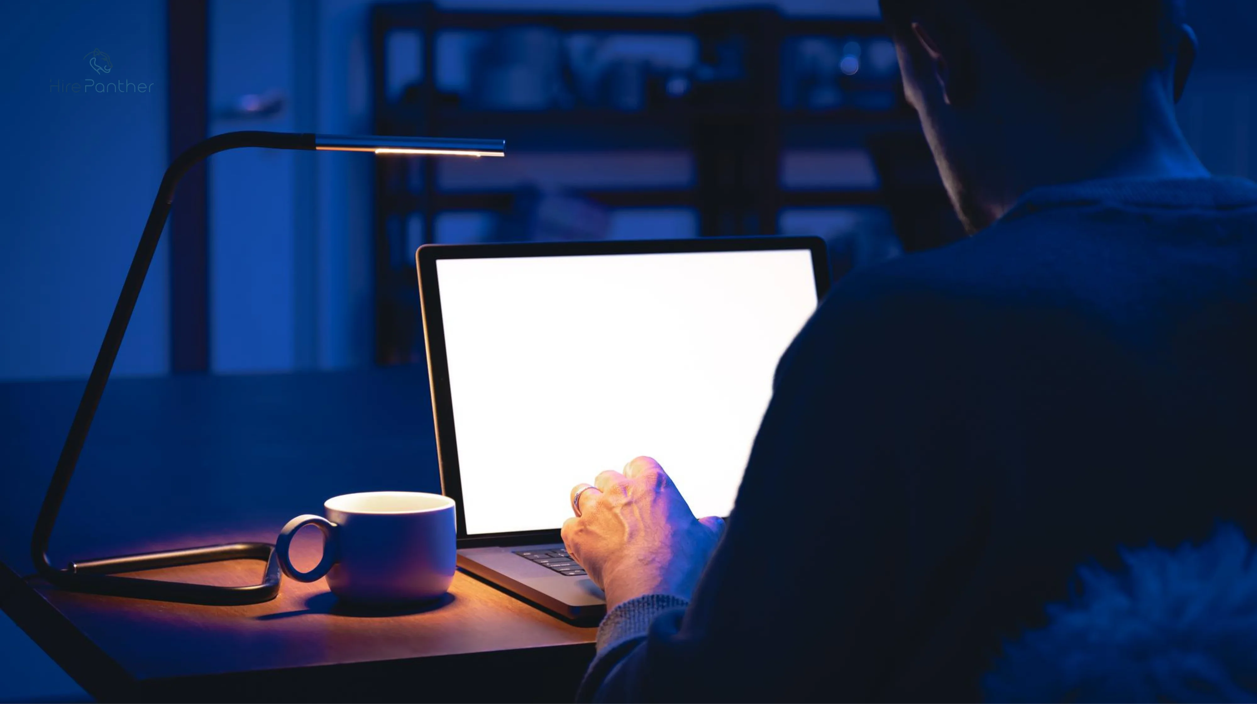 Freelancer alone at night with glowing laptop, coffee mug beside Freelancer alone at night